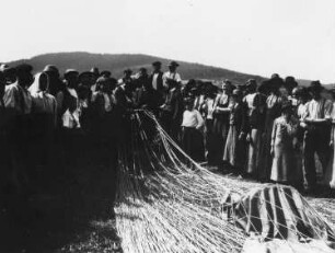 Deutschland (Thüringen?). Ballonfahrt. Nach der Landung. Gruppenaufnahme mit Einheimischen, aufgestellt um den Korb