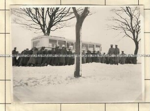 Angehörige der Ordnungspolizei beim Anschieben eines Busses auf einer verschneiten Straße