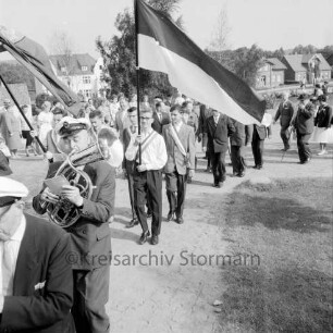 Kindervogelschießen: Umzug: Grünanlage zwischen Matthias-Claudius-Schule und Ahrensböker Straße (im Hintergrund): Blaskapelle, Fahnenträger, Schützen, Stadtvertreter: hinten links Zuschauer, 24. Juni 1961