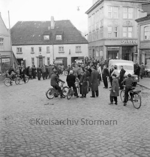 Freiwillige Feuerwehr Bad Oldesloe: Hude: vor Feuerwache, Gerätehaus im "Blauen Haus": Löschfahrzeuge vor Garagentüren: viele Zuschauer, Fahrradfahrer: links Drogerie Rodick: rechts Textilhaus Gebrüder Petersen, Einmündung Besttorstraße, parkender Kleintransporter