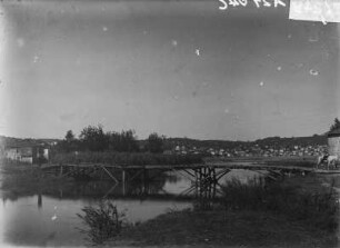 Holzbrücke : Eine Holzbrücke über einen Fluss. Im Hintergrund eine Stadt