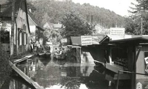 Rathen-Niederrathen. Elbhochwasser in der Mündung des Grünbaches (Amselgrund). Bootsverkehr zwischen Läden und Kiosken am Amselgrundweg