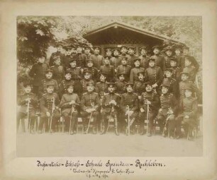 Teilnehmer (ca. vierzig Personen) am Lehrkurs der Infanterie-Schiessschule Spandau vor Waldhütte teils stehend, teils sitzend