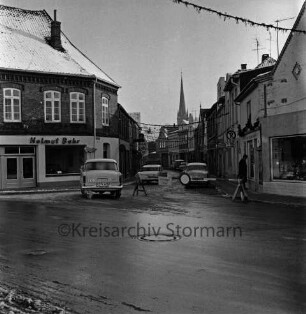 Hindenburgstraße mit Adventsschmuck: vorn Hagenstraße: in der Mitte Absperrung, Pkws und Lkw: Wohn- und Geschäftshäuser: vorn links Autohandel Helmut Bahr: hinten Mitte Turm der Peter-Paul-Kirche: Winter