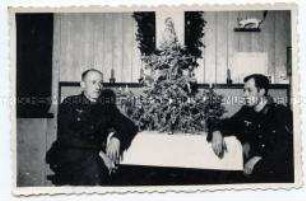 Zwei Heeressoldaten an einem Tisch mit Weihnachtsbaum sitzend