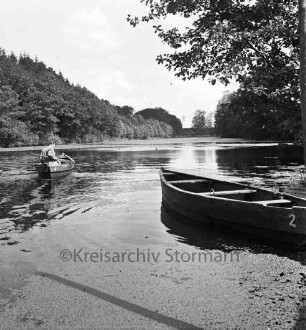 Kupfermühle: Kupfermühlenteich: vorn im Wasser Wasserlinsen: rechts Ruderboot und Baum: hinten links Mann in zweitem Ruderboot: hinten Wald