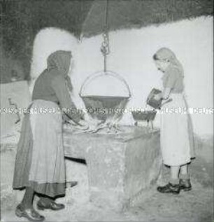 Arbeitsmaid des Reichsarbeitsdienstes am Herdfeuer mit Suppenkessel
