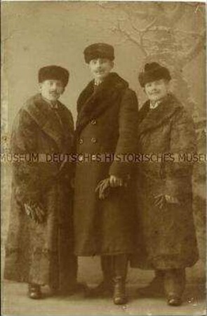 Atelieraufnahme von drei jungen Männern in Wintermänteln