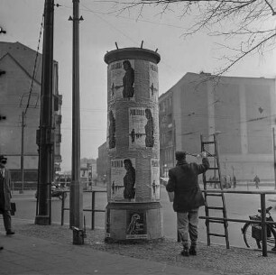 Plakatankleber eine Litfass-Säule beklebend, 1964. SW-Foto © Kurt Schwarz.