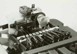 Mechanische Blindenschrift-Stenografiermaschine mit 7 Tasten zum Anschlagen der Punkte, Zwischenraumtaste und Streifenschreiber. Detail: Typenhebelgetriebe, Typenträger mit Stiften und Streifenführung : Mechanische Blindenschrift-Stenografiermaschine mit 7 Tasten zum Anschlagen der Punkte, Zwischenraumtaste und Streifenschreiber. Detail: Typenhebelgetriebe, Typenträger mit Stiften und Streifenführung. Baujahr: 1950/1955; Hersteller: Firma Karl Neubert . Verwalter: Sächsische Landesbibliothek - Staats- und Universitätsbibliothek Dresden (SLUB), Stenografische Sammlung, Inventar-Nummer R i 0027