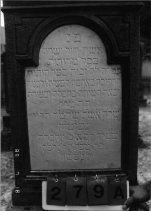 Grabstein 279 (Index: 99797806) Material: Sandstein, weiß, Marmorplatte Zustand: gut Maße HxBxT: 166x60x22 cm Beschreibung: Stele, Rundbogenaufsatz rechteckig erhöht, getreppter Sockel Symbolik: Mohnpflanze Steinmetz: Henne: Grabstein 279A