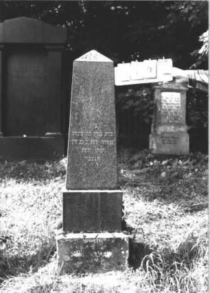 Grabstein 114 (Index: 100106426) Material: grau-schwarzer Granit, unterster Sockel Sandstein Zustand: gut Maße HxBxT: 144x37x19 cm Beschreibung: obeliskenartige Stele, getreppter Sockel: Grabstein 114