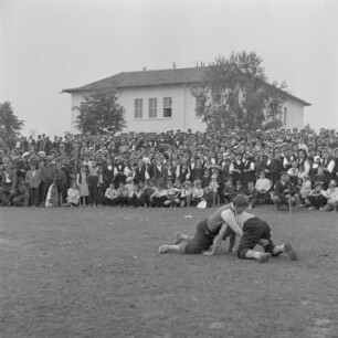 Dorffest. Dorfbewohner als Zuschauer verfolgen der Darbietung des Ringkampfes der Schüler