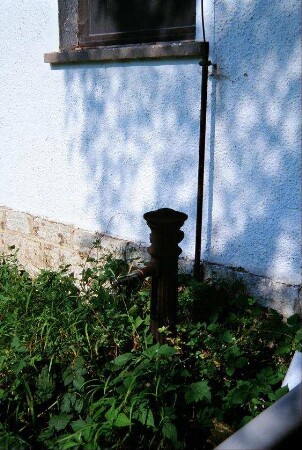 Pumpe (?) vor einem Haus