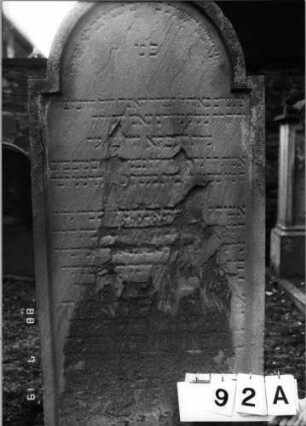 Grabstein 92 (Index: 100094796) Material: Sandstein Zustand: verwittert, abgeblättert, Textverlust Maße HxBxT: 170x70x12 cm Beschreibung: Stele, eingezogener Rundbogenabschluß: Grabstein 92A