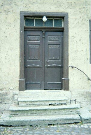 3 Kalksteinstufen vor einer zweiflügeligen alten Haustür
