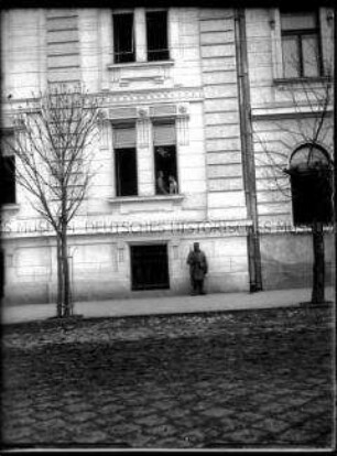 Soldat vor einem mehrstöckigen Wohnhaus, 1. Weltkrieg