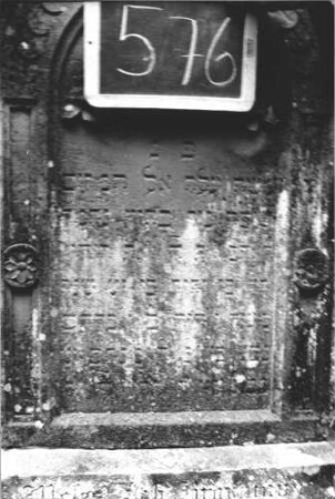 Grabstein 576 (Index: 99895386) Material: Sandstein Zustand: leicht verwittert und bewachsen Maße HxBxT: 137x57x22 cm Beschreibung: Stele mit Rundbogenabschluss, kleiner Verdachung und Mittelakroter; Sockel Symbolik: Kranz mit Bändern: Grabstein 576 (1)