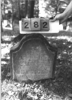 Grabstein 282 (Index: 99609919) Material: Sandstein Zustand: Stele zerbrochen, nur Oberteil erhalten, stark verwittert, weitgehender Textverlust Maße HxBxT: 49x44x11 cm Beschreibung: oberes Bruchstück einer Stele, Konvexbogenabschluß, Schriftfeld erhaben: Grabstein 282