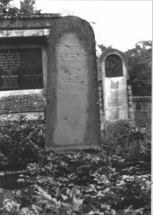 Grabstein 101 (Index: 100114249) Material: Sandstein Zustand: stark verwittert mit Textverlust Maße HxBxT: 160x60x30 cm Beschreibung: konische Stele, getreppter Sockel, Rundbogenabschluß: Grabstein 101