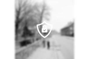 Dorfstraße mit Kindern auf Fußgängerweg: links Garten mit Bäumen: im Hintergrund Bauernhäuser