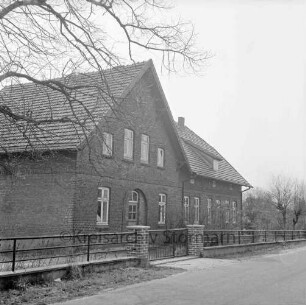 Wohnhaus: ehemalige Volksschule: davor Zaun: links Baumäste