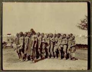 Nahaufnahme einer Gruppe afrikanischer Männer, dicht gedrägt auf einem Dorfplatz stehend