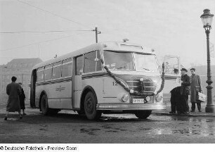 Personen betrachten einen mit Girlanden geschmückten Omnibus H6B