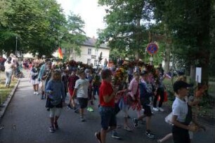 Bad Oldesloe: Kindervogelschießen: Am Bürgerpark, Blickrichtung Westen: Einzug auf den Exer: Festumzug Klaus-Groth-Schule Klasse 4a, teils mit Blumenschmuck: im Hintergrund Bundesflagge und Jugendfreizeitstätte (JuZe): 13. Juli 2023
