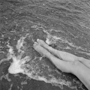 Frauenbeine im Wasser der ankommenden Wellen am Strand von Henkenhagen (heute: Ustronie Morskie)