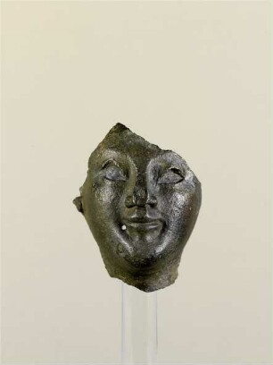 Fragment eines Kopfes, Gesicht, Teile vom Hals, Stirn und rechtem Ohr, Loch unterhalb des rechten Mundwinkels, Nase eingedrückt, Hohlguss, Augen waren eingelegt