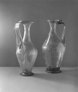Zwei Henkelkannen mit Standreif, rechts (Inv.-Nr. 38,6, Höhe: 32,5 cm), in der linken ein Parfumflakon