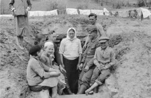 Zweiter Weltkrieg. Frontbilder. Sowjetunion. Einheimische und Angehörige der deutschen Wehrmacht am Eingang zu einem Erdbunker