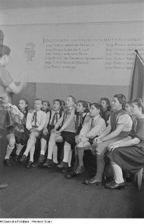 Chorleiter mit Akkordeon und singenden Pionieren