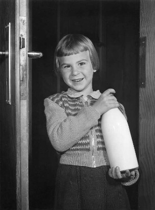 Kinderbilder. Porträt eines kleinen Mädchens, mit Milchflasche in einer geöffneten Tür stehend