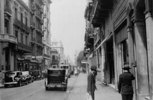 Straße : Blick in eine Straße mit Automobilen, Personen und Gebäuden