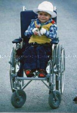Kleines, behindertes Kind in einem Rollstuhl (Altersgruppe 18-21)