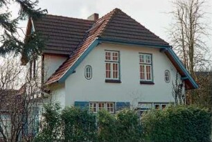 Hasselbusch 7: giebelständiges Wohnhaus: Straßenfront mit Eingangstür: Traufseite mit vorkragendem Zwerchhaus: im Vordergrund Gartenhecke