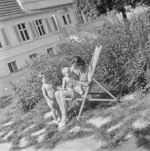 Mutter im Liegestuhl sitzend mit ihren zwei Kindern