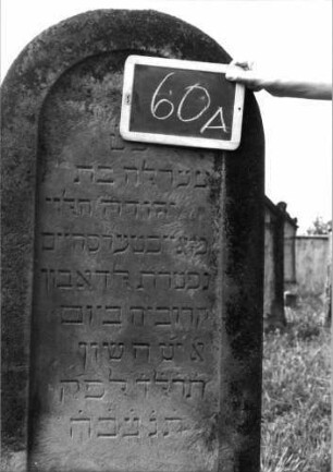 Grabstein 60 (Index: 99936994) Material: Sandstein Zustand: leicht verwittert Maße HxBxT: 149x57x16 cm Beschreibung: Stele, Sockel, Rundbogenabschluß, Schriftfeld eingetieft: Grabstein 60A