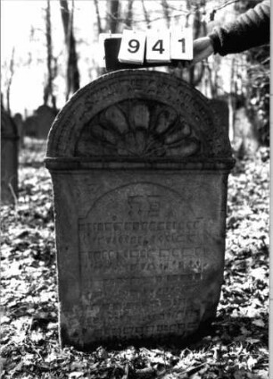 Grabstein 941 (Index: 99902478) Material: Sandstein Zustand: eingesunken Maße HxBxT: 105x67x12 cm Besonderheit: kulturhistorisch wertvoll / künstl.-formale Gründe: Grabstein 941