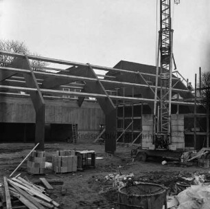 Tremsbüttel-Dorf: Gemeindezentrum: Mehrzweckhalle im Bau: Blick von außen auf Dachkonstruktion aus Holz-Leimbinder: rechts Kran: im Vordergrund Bretter und Baumaterial