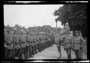 Nicht identifizierbare Ortschaft in Nordfrankreich oder Belgien: Soldaten mit Pickelhaube in Aufstellung auf einer breiten gepflasterten Parkstraße, davor ein Offizier mit Pickelhaube [Ludwig III. von Bayern (?)] zu Pferd (Seitansicht, Nahaufnahme)