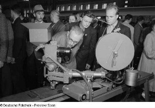 Besucher betrachten ein Exponat der Leipziger Herbstmesse 1954