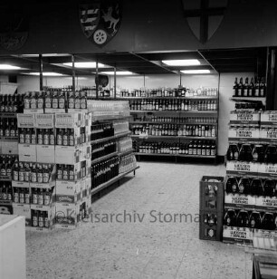 Käselau: Kaufhaus: Bahnhofstraße: vor Eröffnung am 23. November 1972: Innenansicht: Getränke-Abteilung: Regale mit Spirituosen, rechts Getränke-Kästen