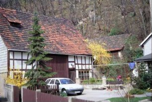 Blick in einen Hof auf eine Scheune, dahinter Hang, vor dem weitere Scheune steht