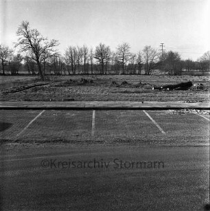 Heinrich-Hertz-Straße: vorne Straße, Fußgängerweg, Parkstreifen: Gewerbeflächen vor Erschließung: Knick gerodet, Graben: hinten Baum, Knick: im Hintergrund Bäume, Büsche, Strommast