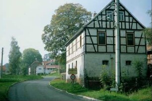 Ortseingangsschild; Häuser entlang der Straße