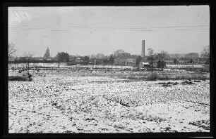Vendin-le-Vieil (Dep. Pas-De-Calais): Blick über schneebedeckte Felder auf Häuser, einen Schlot und eine Kirche