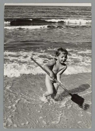 Kind mit einer Schaufel am Strand